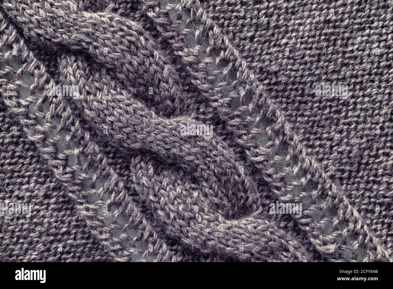 Openwork pattern knitted with needles from pink wool yarn. Stock Photo