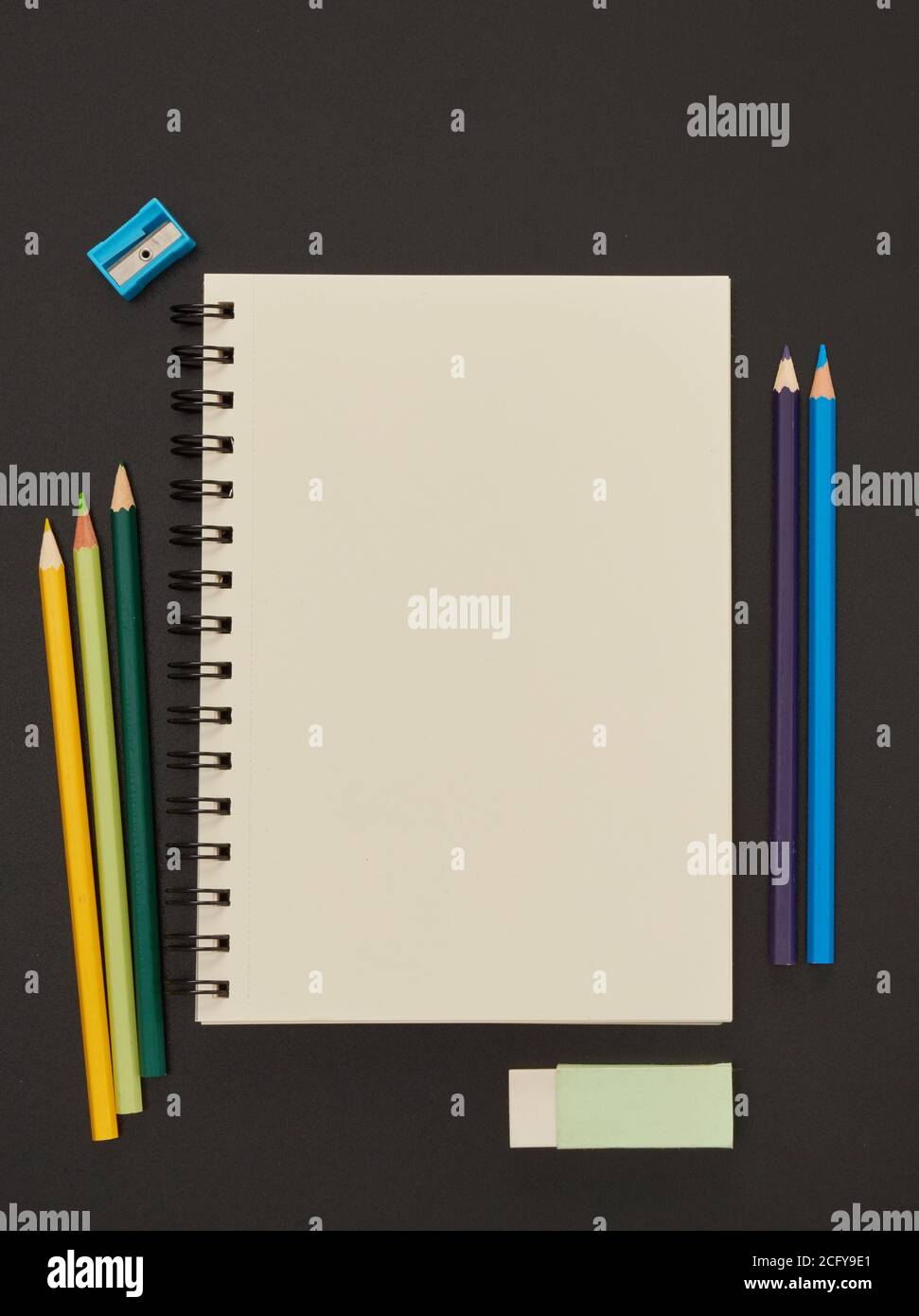 Notebook and multi-colored pencils on blackboard Stock Photo