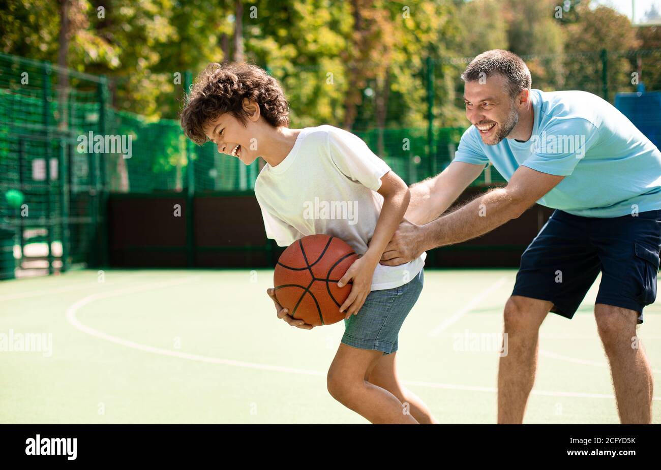 Sportive dad teaching his son how to play basketball Stock Photo Alamy