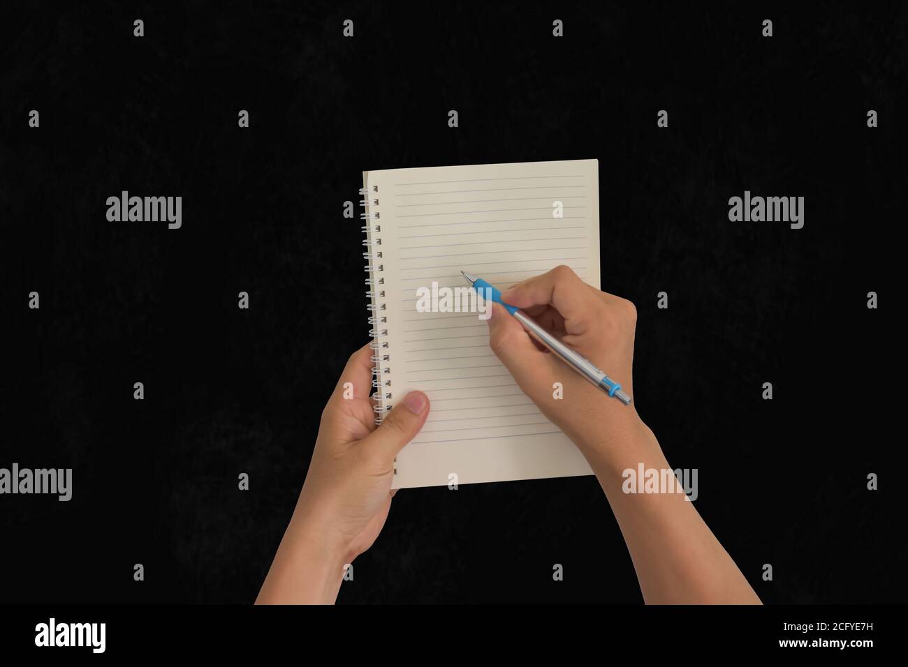 Hand holding pen, with a blank notes over blackboard background. Design concept Stock Photo
