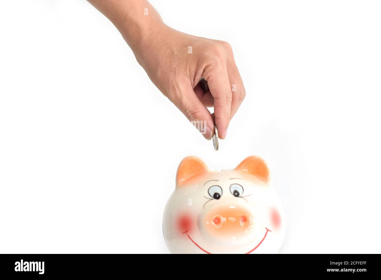 Hands putting coin into a piggy bank on white background. Saving and ...