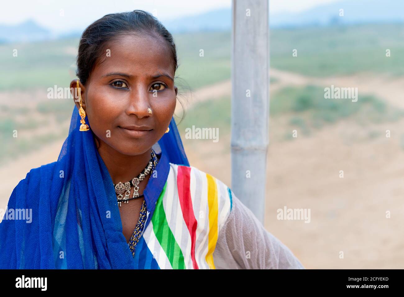 Portrait of nomadic Kalbeliya gypsy woman with beautiful black hair in colorful Indian clothes in Thar desert in Pushkar, Rajasthan, India. Stock Photo
