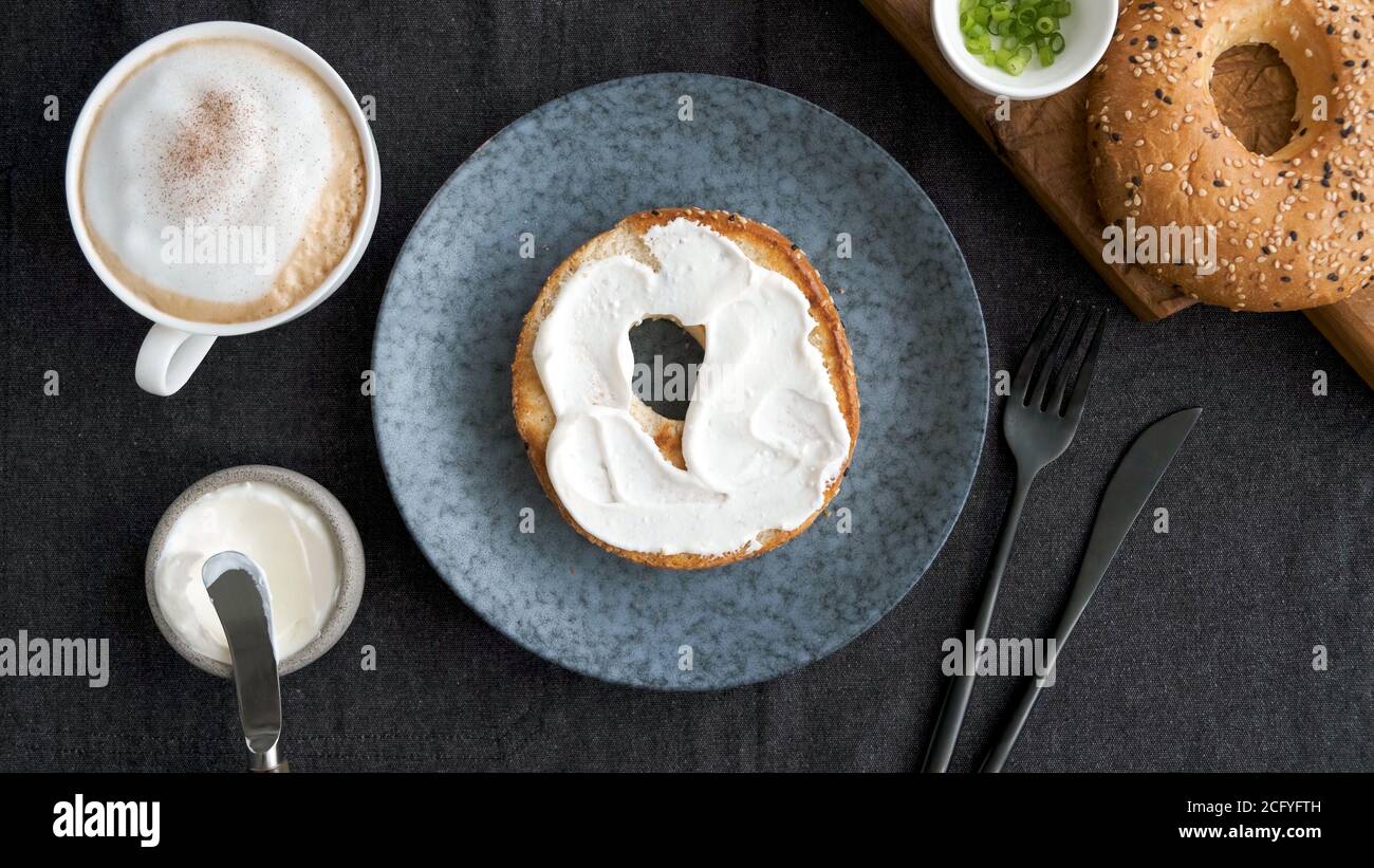 Toasted bagel with cream cheese and cup of coffee for breakfast, top view Stock Photo