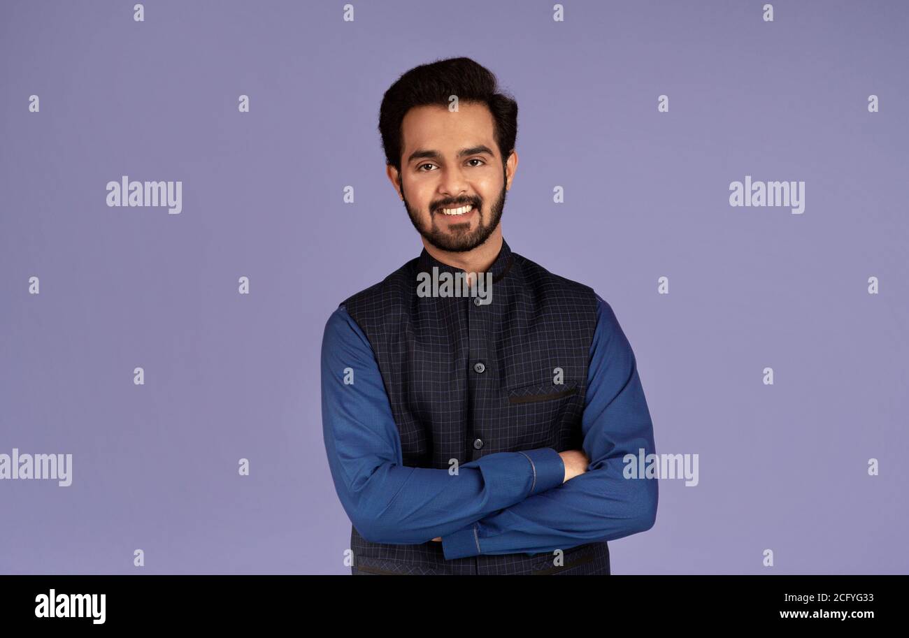 Portrait of smiling Indian guy crossing his arms on lilac background ...