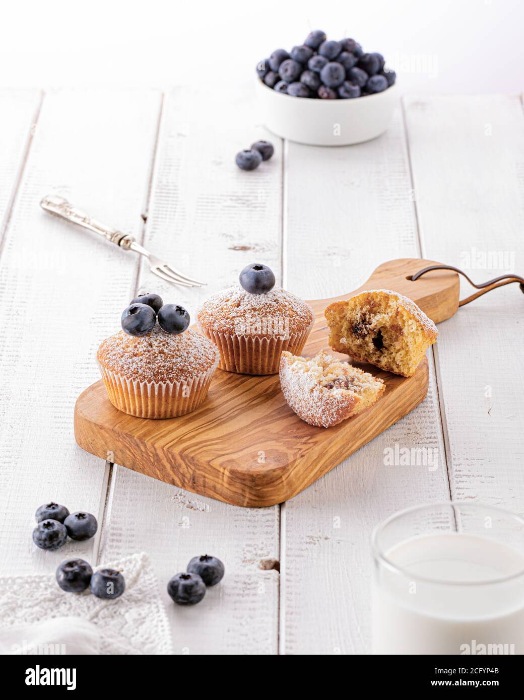 Fresh baked blueberry muffins on wooden board on a white wooden table in the morning light Stock Photo