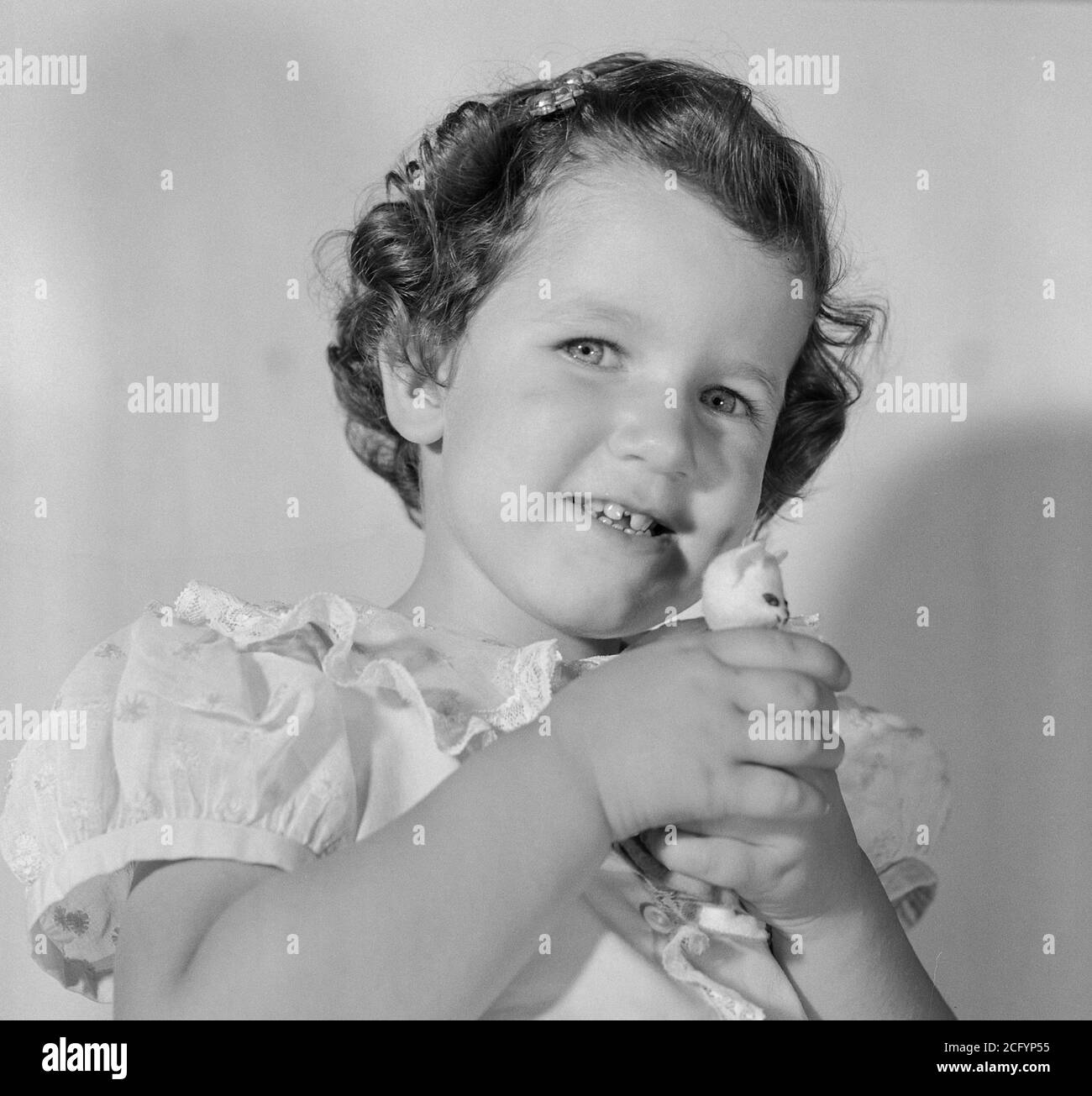 Toddler holds a small stuffed animal, 1950s, USA Stock Photo