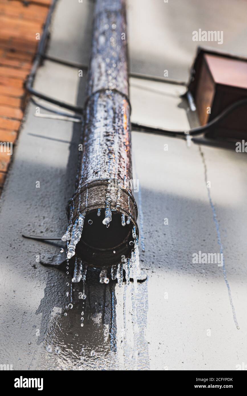 Dripping Rusted Iron Water dripping down a rusty drainage iron pipe with icicles due to ...