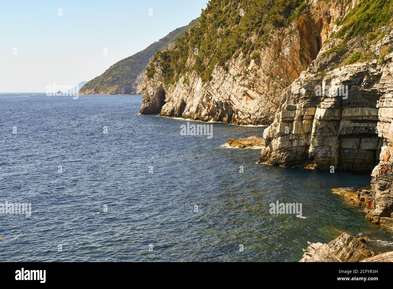 Scenic view of the bay with the Lord Byron's Grotto and people on the rocks in a sunny summer day, Porto Venere, La Spezia, Liguria, Italy Stock Photo