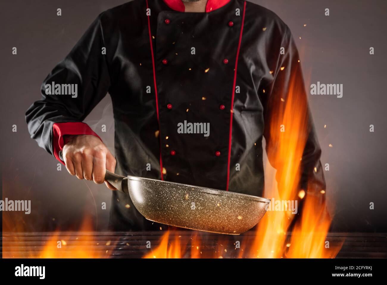 Closeup of chef holding empty frying pan above grill. Concept of food preparation, ready for product placement. Stock Photo