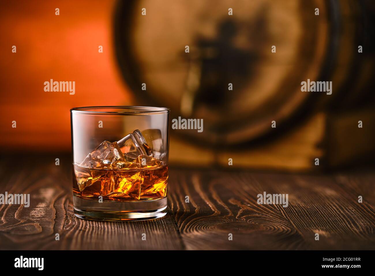 Glass of whisky with ice with barrel on background (soft focus photo with shallow deph of field) Stock Photo