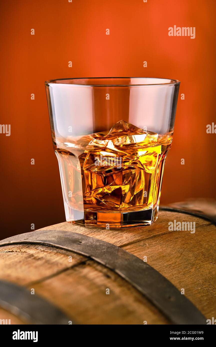 Glass of whisky with ice on the top of barrel (soft focus photo with shallow deph of field) Stock Photo