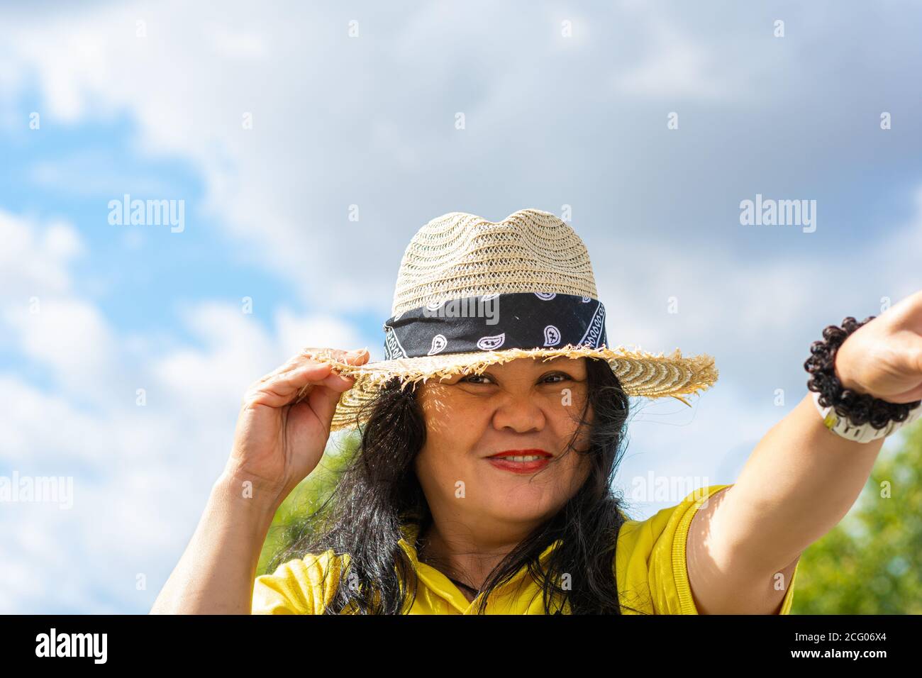 A middle-aged Asian woman, in her 50s, with a straw hat.  Stock Photo