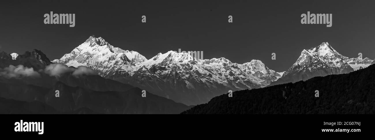 A panoramic view of Mt Kanchenjunga in monochrome with the entire mountain range visible in Sikkim India with dark foreground and background Stock Photo