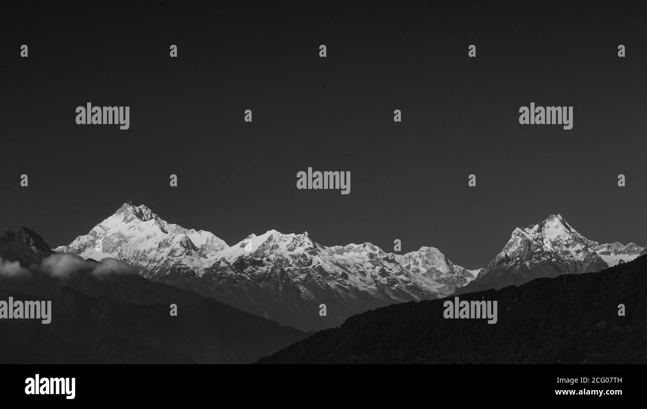 A panoramic view of Mt Kanchenjunga in monochrome with the entire mountain range visible in Sikkim India with dark foreground and background Stock Photo