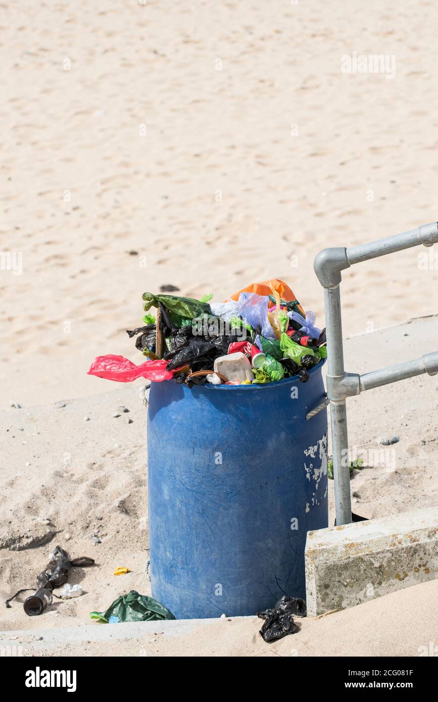 A refuse bin overflowing with plastic rubbish on a beach. Stock Photo