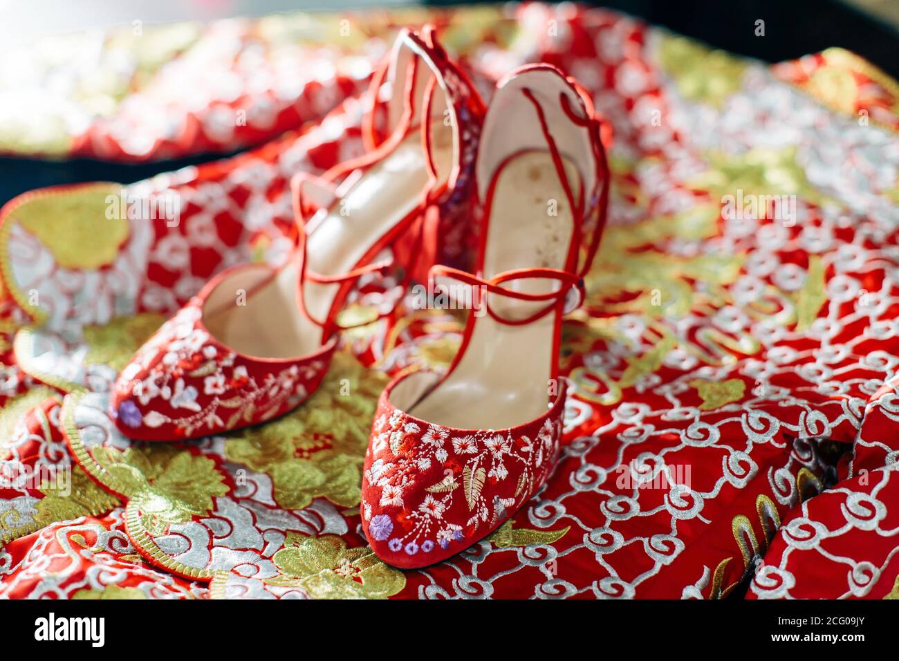 close up of a pair of red color chinese wedding shoes with intricate oriental patterns 2CG09JY