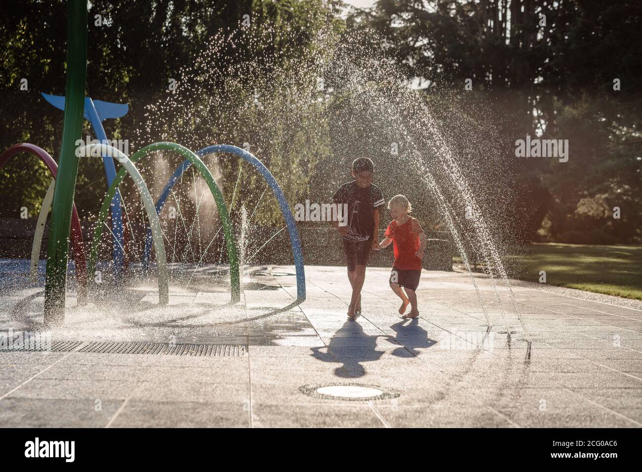 Brothers running in water at playground in New Zealand Stock Photo