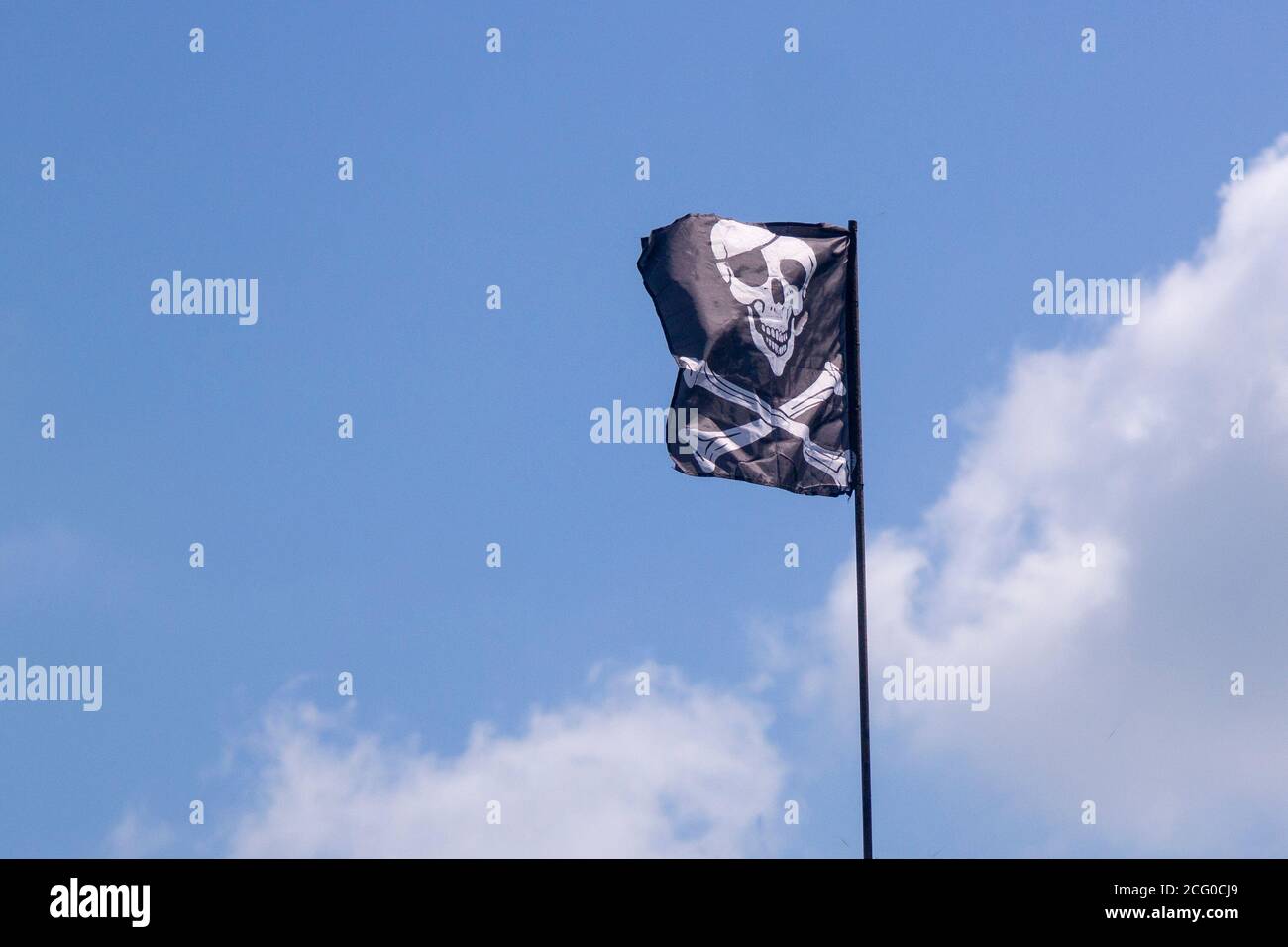 pirate flag develops in the wind, skull with bones, Jolly Roger,the symbol of the robbery Stock Photo