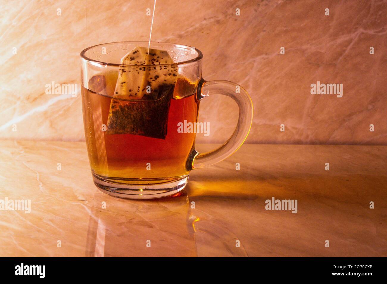 a tea bag has just been dropped into a mug of boiling water Stock Photo