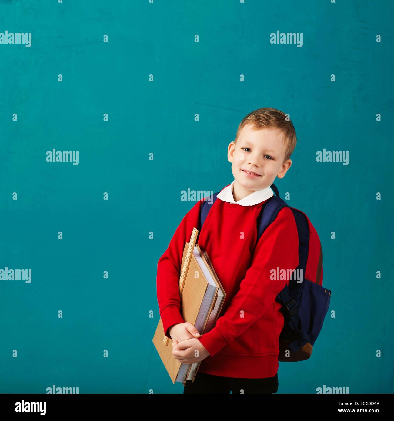Cheerful thoughtful little school boy in school uniform with backpack ...