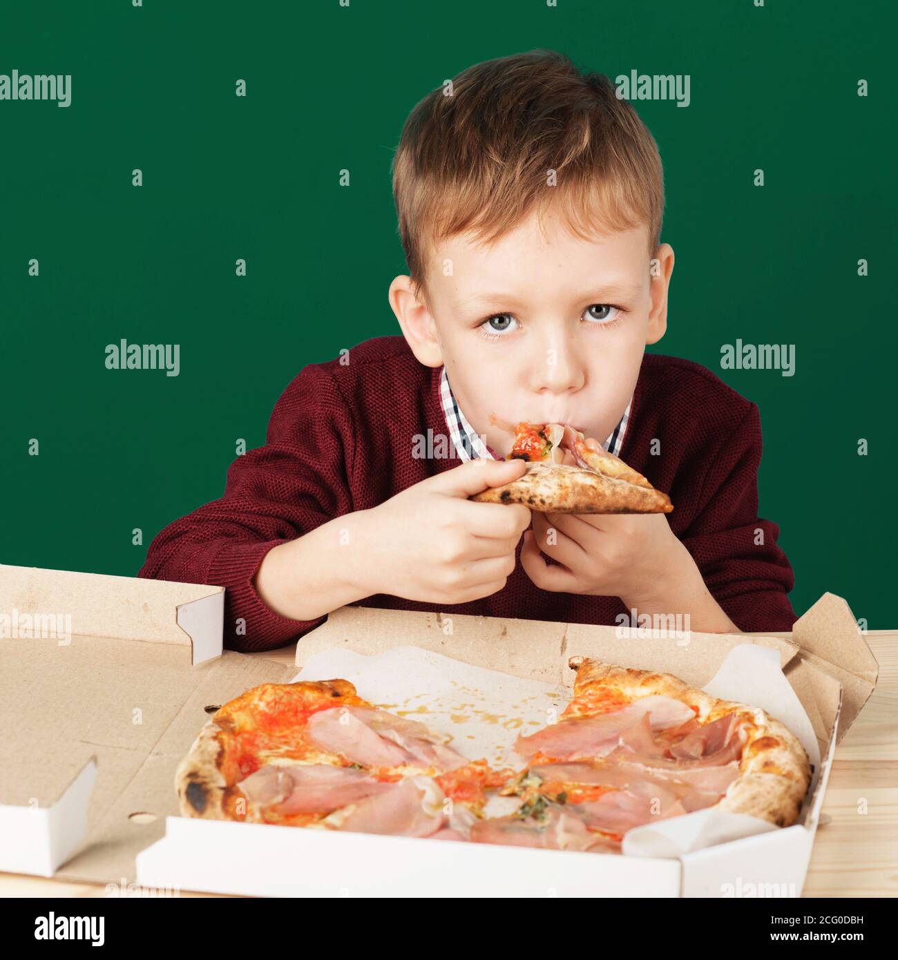 Children eat Italian pizza in the cafe. School boy is eating pizza for