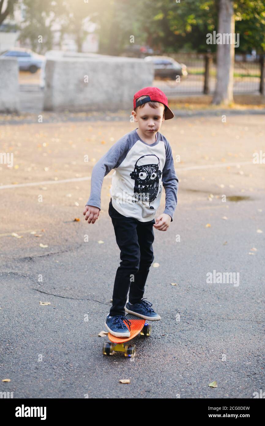 Little urban boy with a penny skateboard. Young kid riding in the park ...