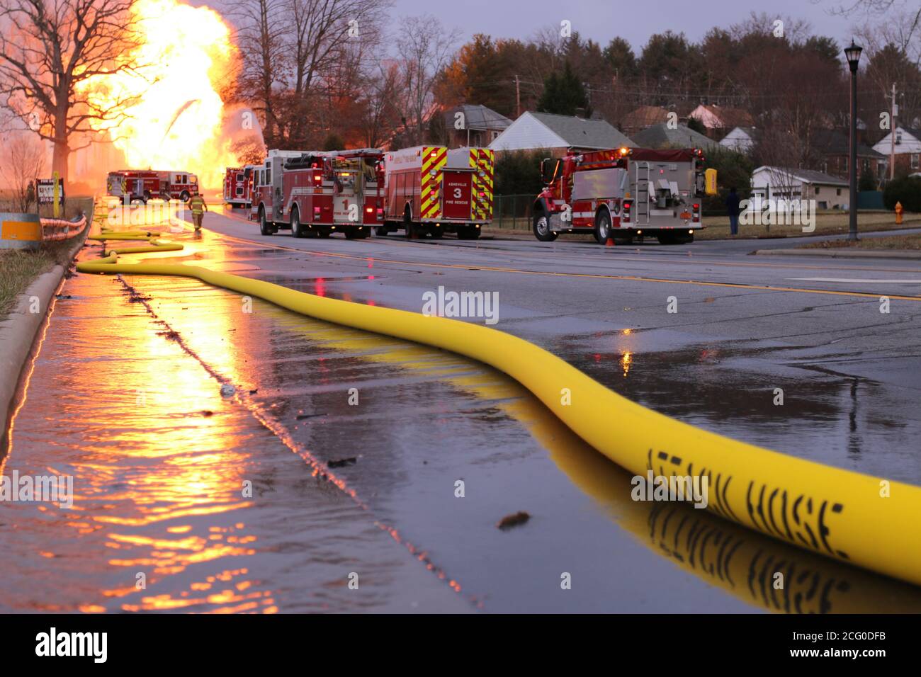 A fire hose supplies water for containment of a fire that resulted from a gas line rupture Stock Photo