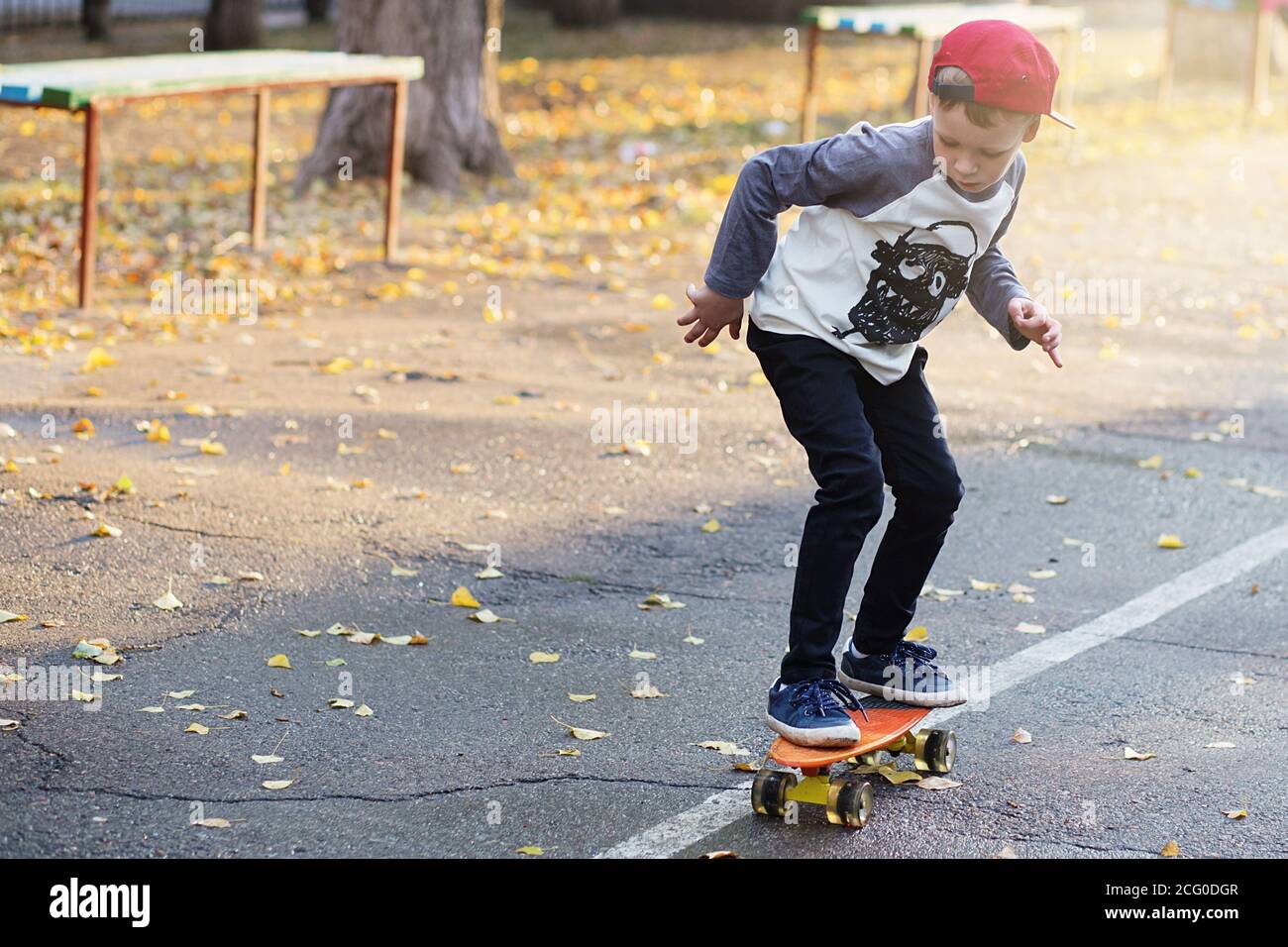 Little urban boy with a penny skateboard. Young kid riding in the park ...