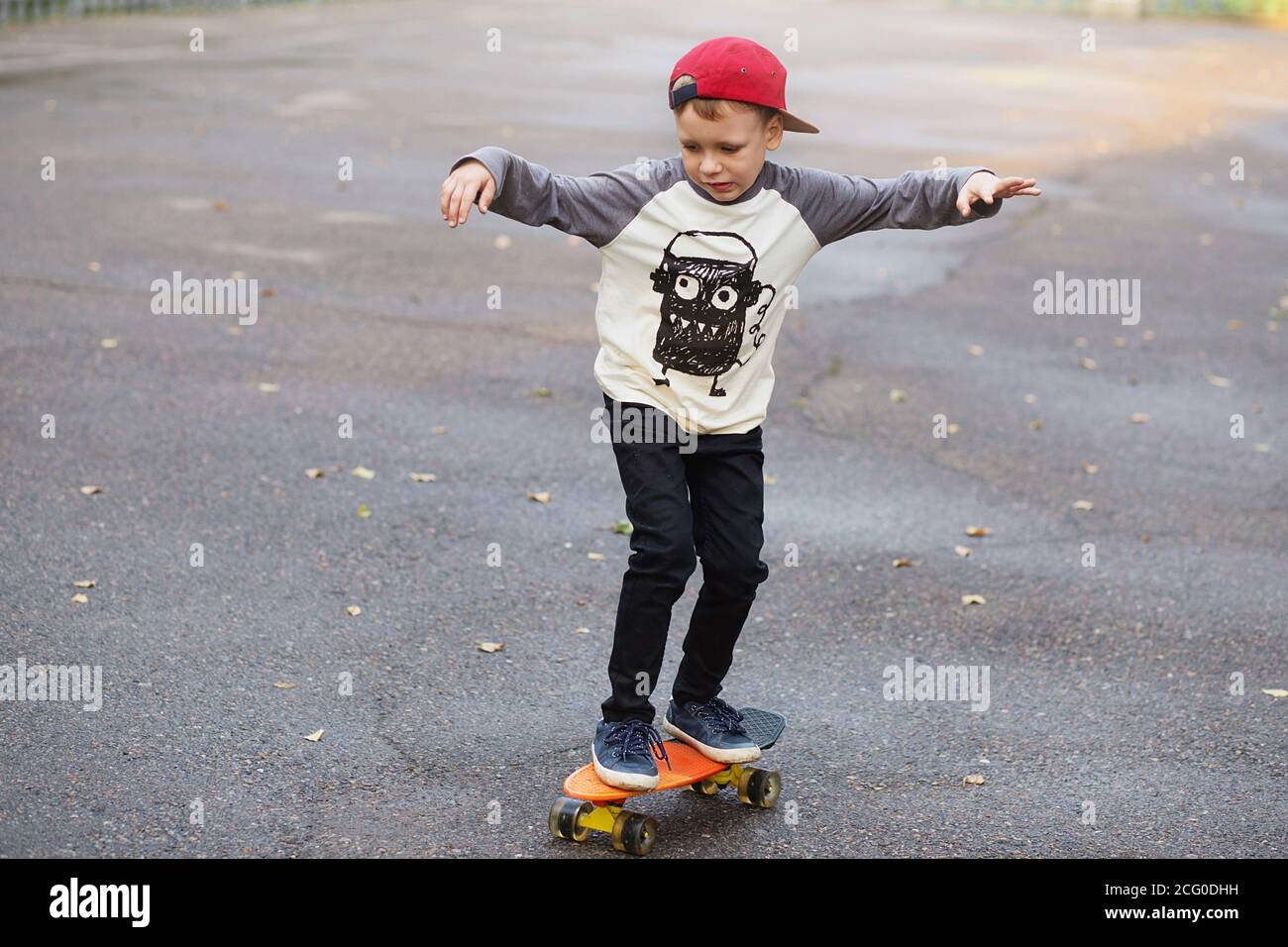 Little urban boy with a penny skateboard. Young kid riding in the park ...
