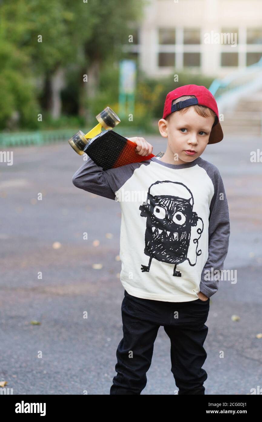 Little urban boy with a penny skateboard. Young kid riding in the park ...