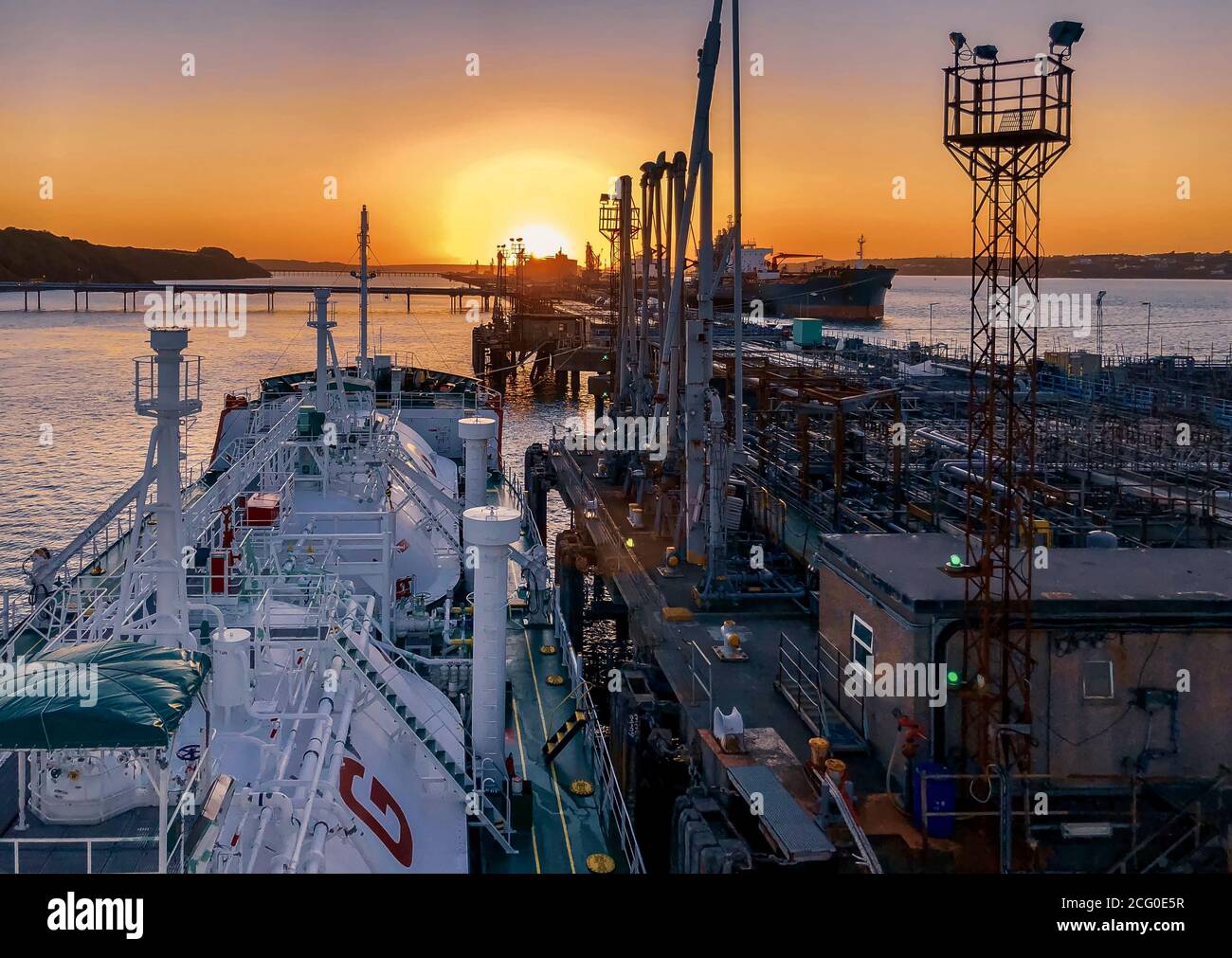 spectacular sunset and ship loading alongside of a gas terminal Stock Photo