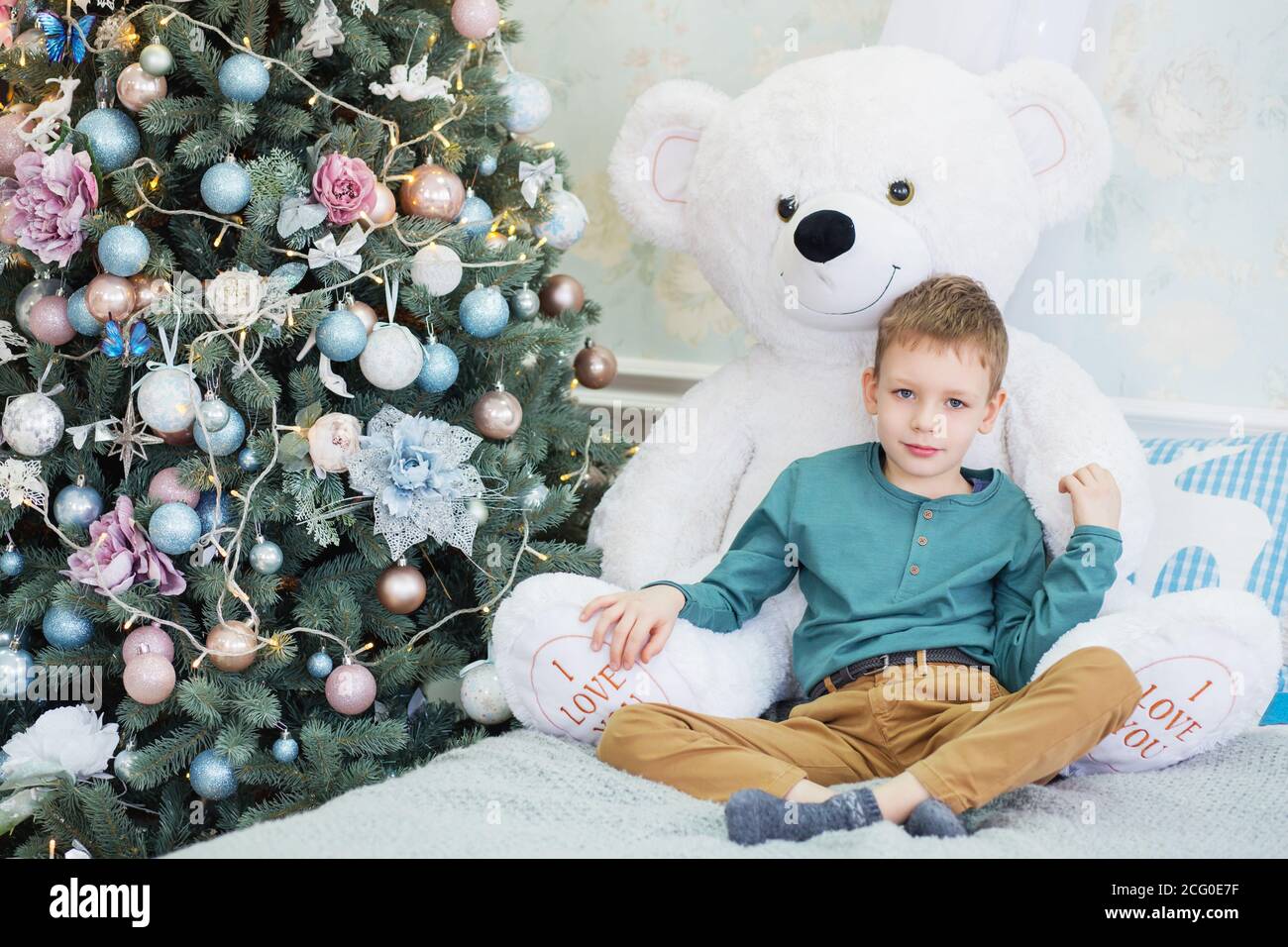 Portrait of a cute little boy hugging a soft teddy bear in interior ...