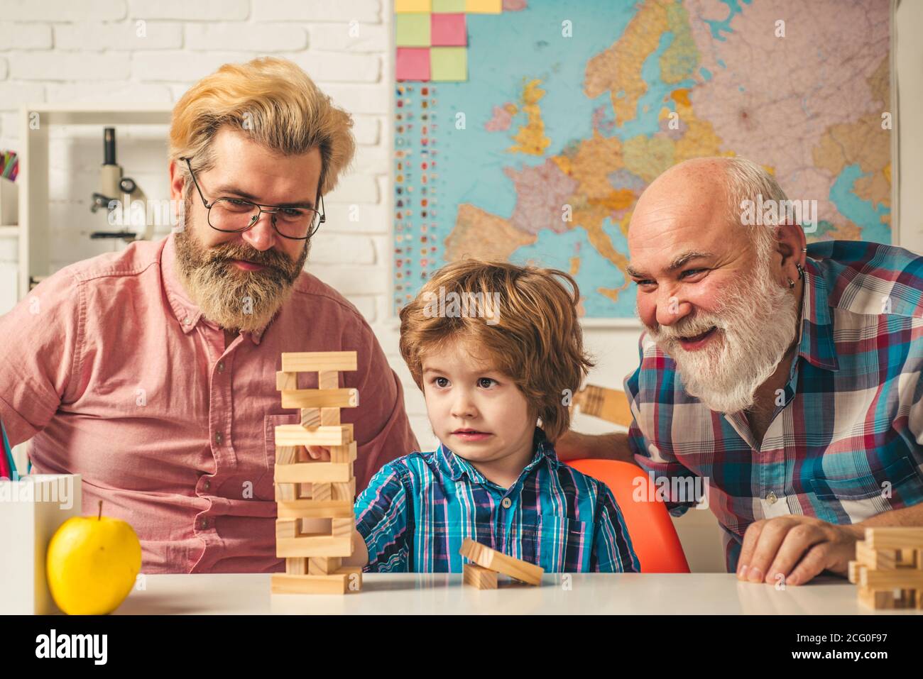 Male generations friendship. Laughing grandparent with son and grandchild relaxing spending weekend at home. Playing Jenga. Stock Photo