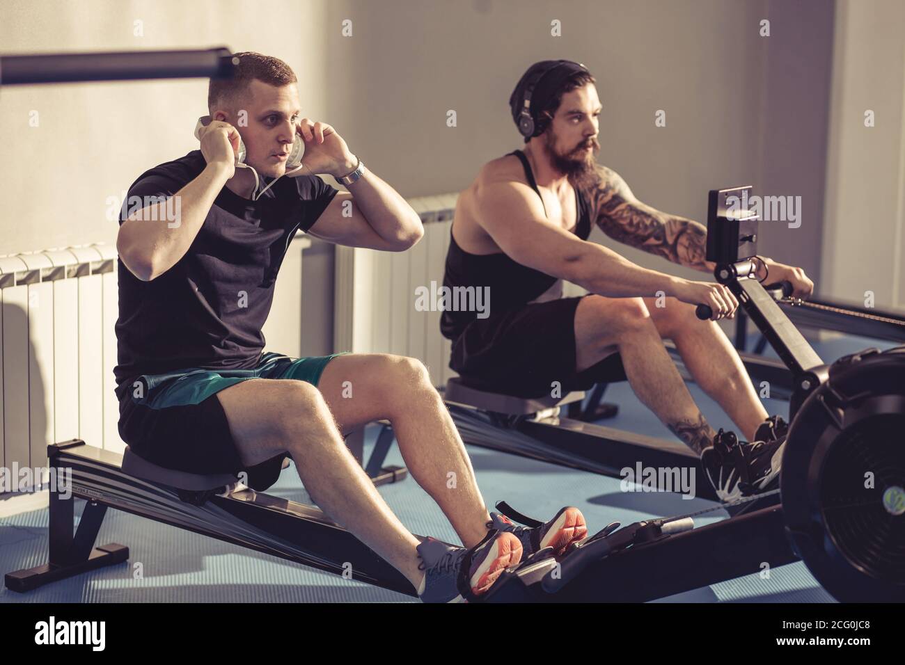 Happy friends training on rowing machine in gym Stock Photo