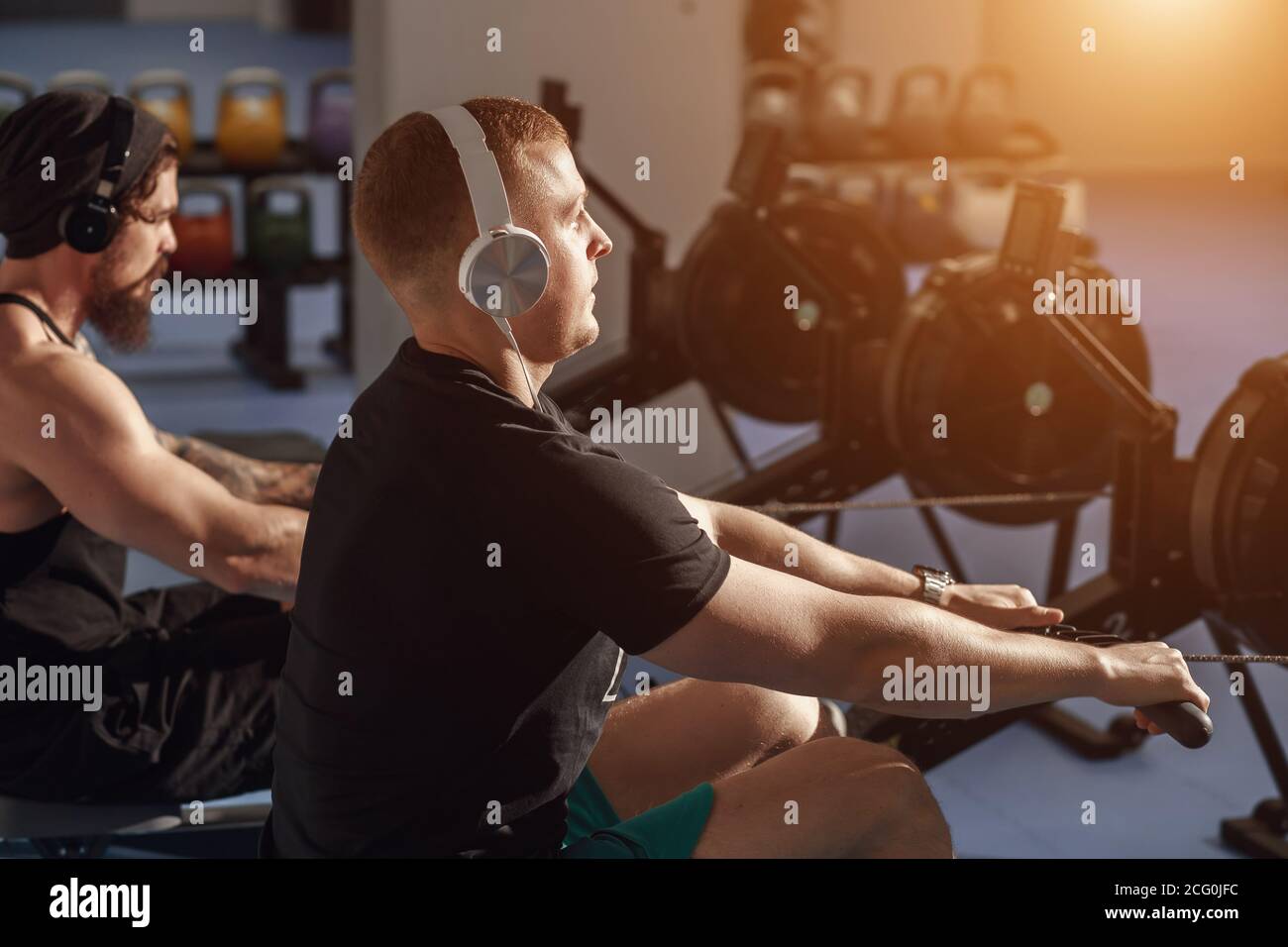 Happy friends training on rowing machine in gym Stock Photo