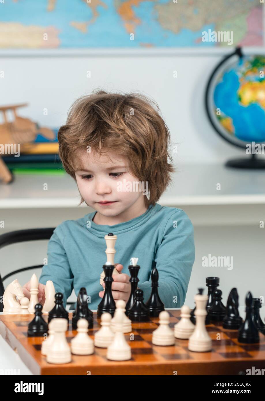 Kids chess school. Concentrated boy developing chess strategy, playing board game. Stock Photo
