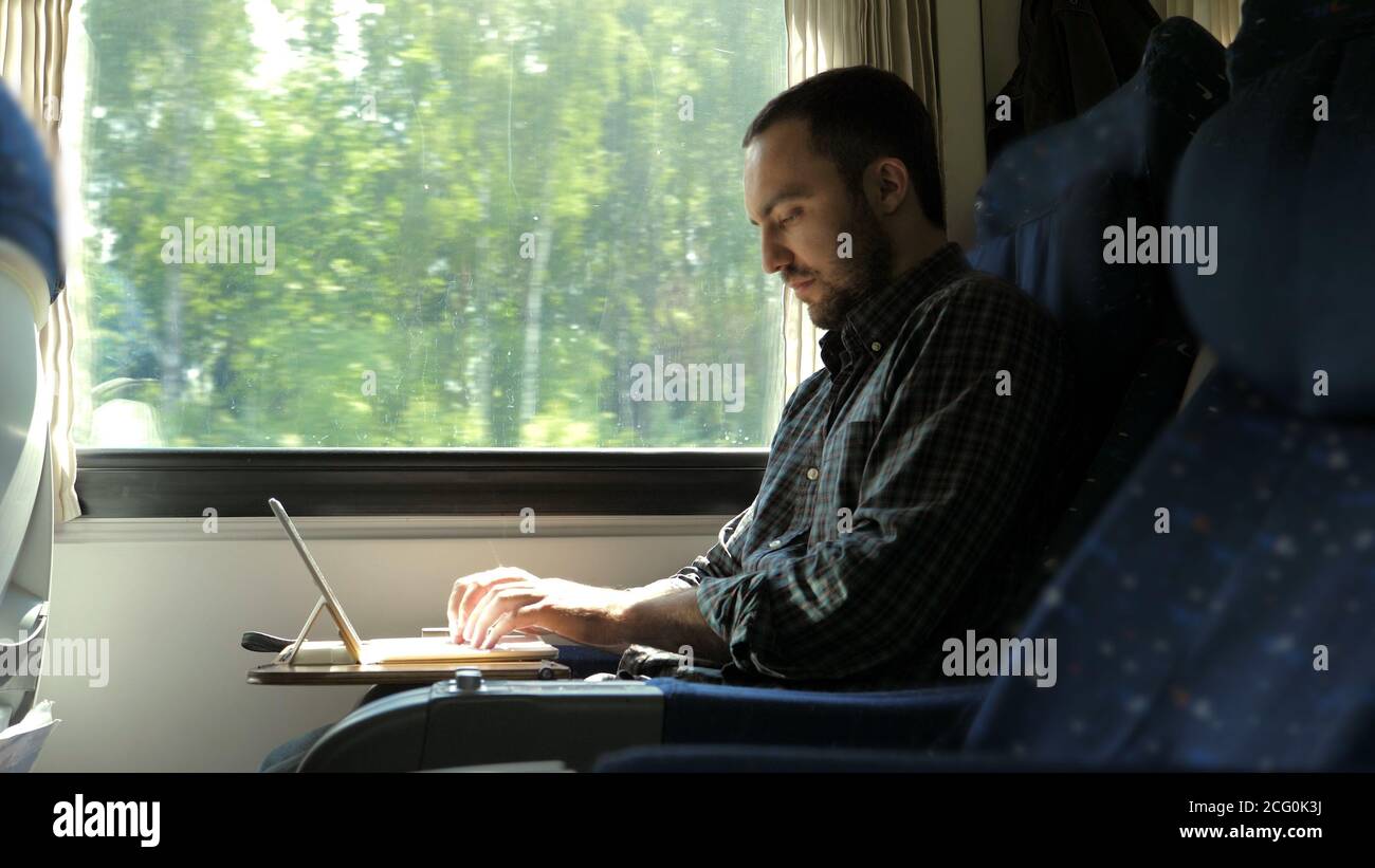 Man working on laptop tablet computer in train Stock Photo - Alamy