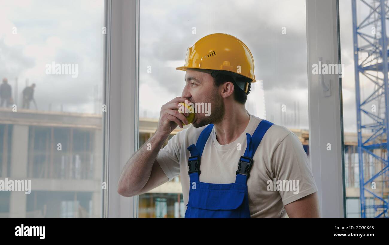 Construction worker having a break and eating apple. Stock Photo