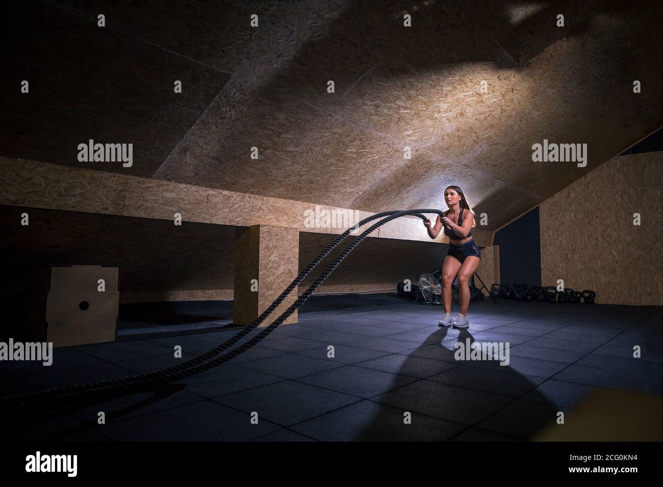 Strength Rope Models Young woman doing strength training using heavy ropes at the gym ...