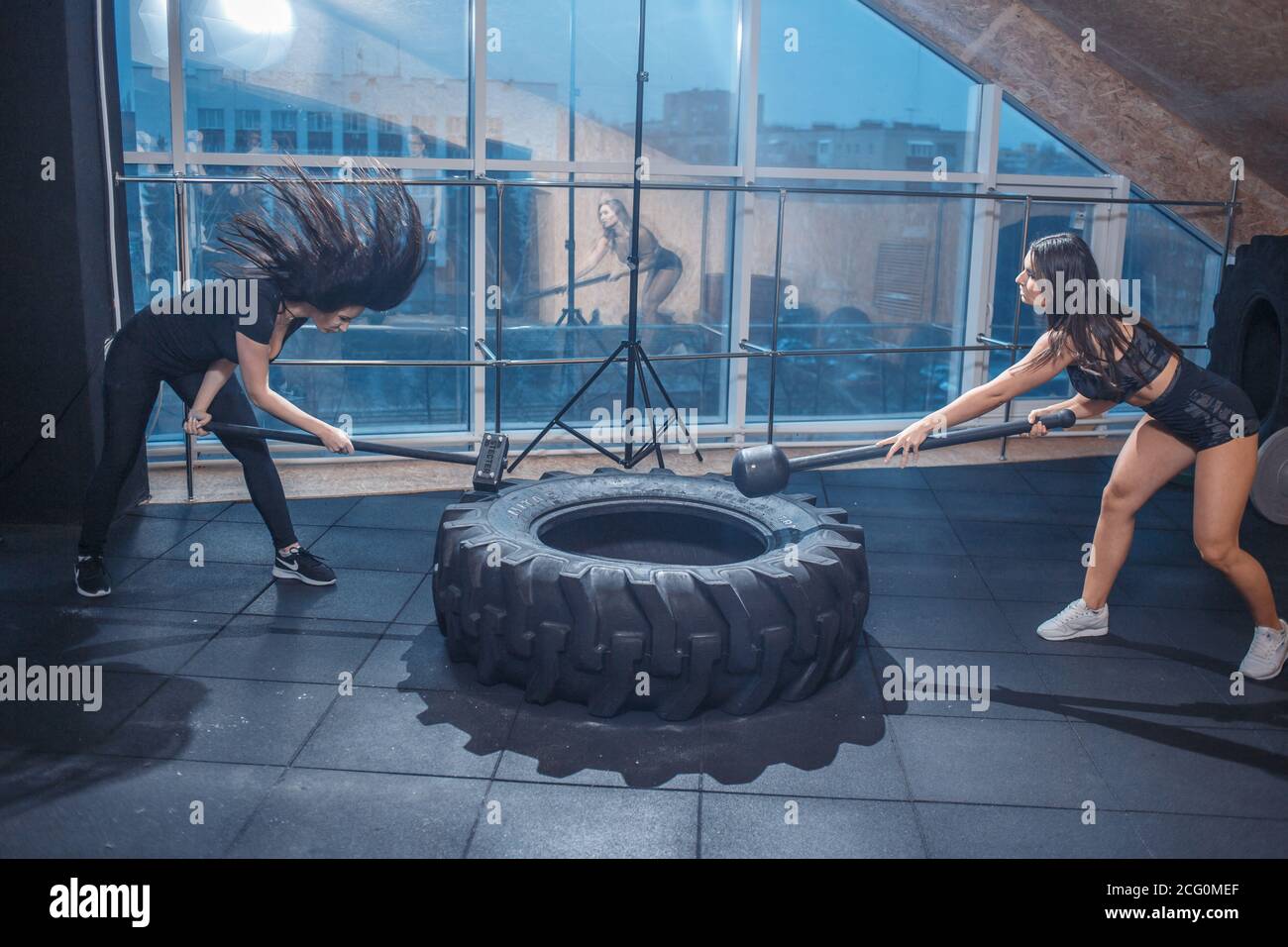 Female fitness model hitting a tractor tyre with hammer in a cross fit gym during intense training Stock Photo Alamy