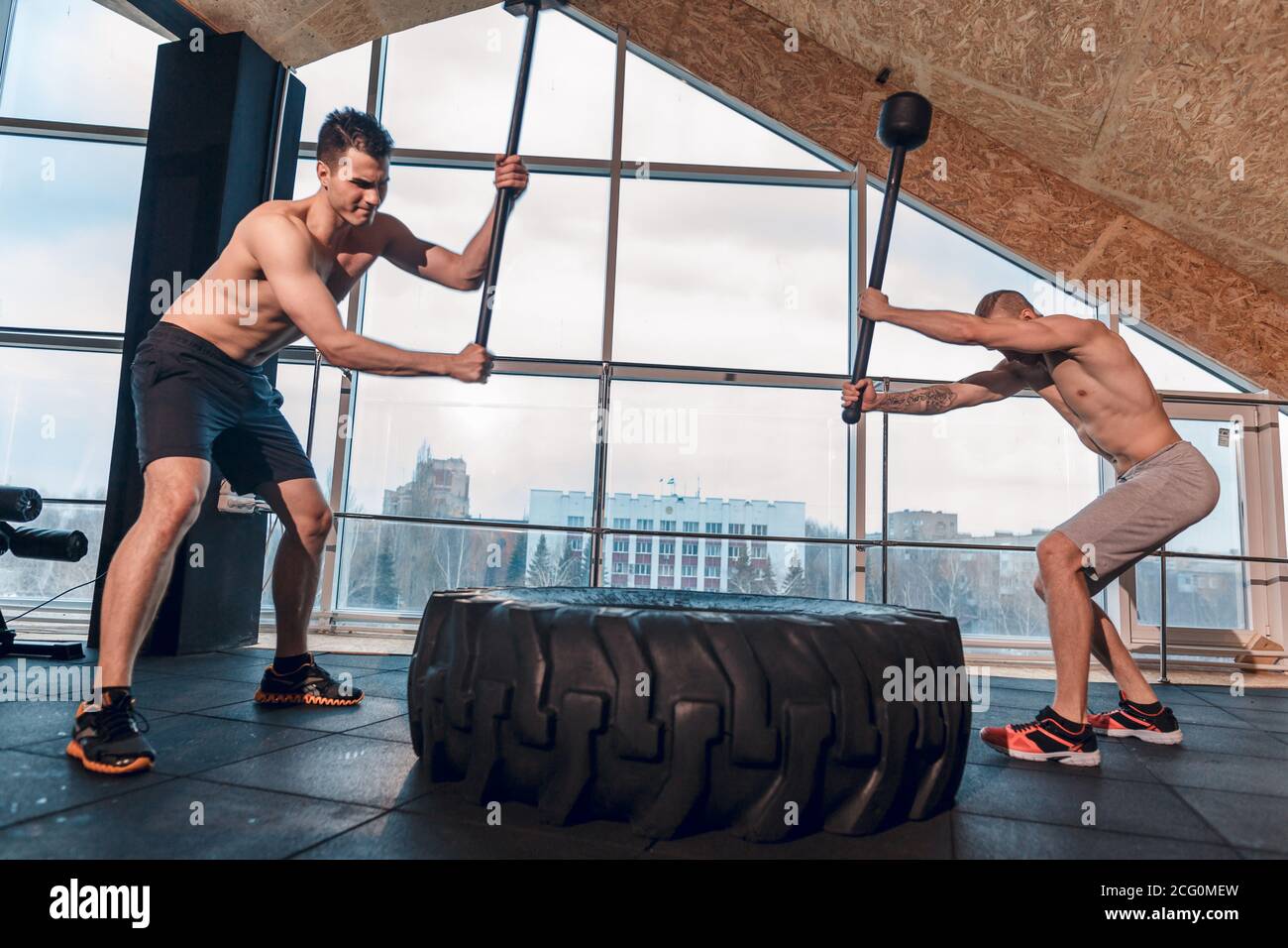 two Male fitness models training workout witth heavy and big tire and