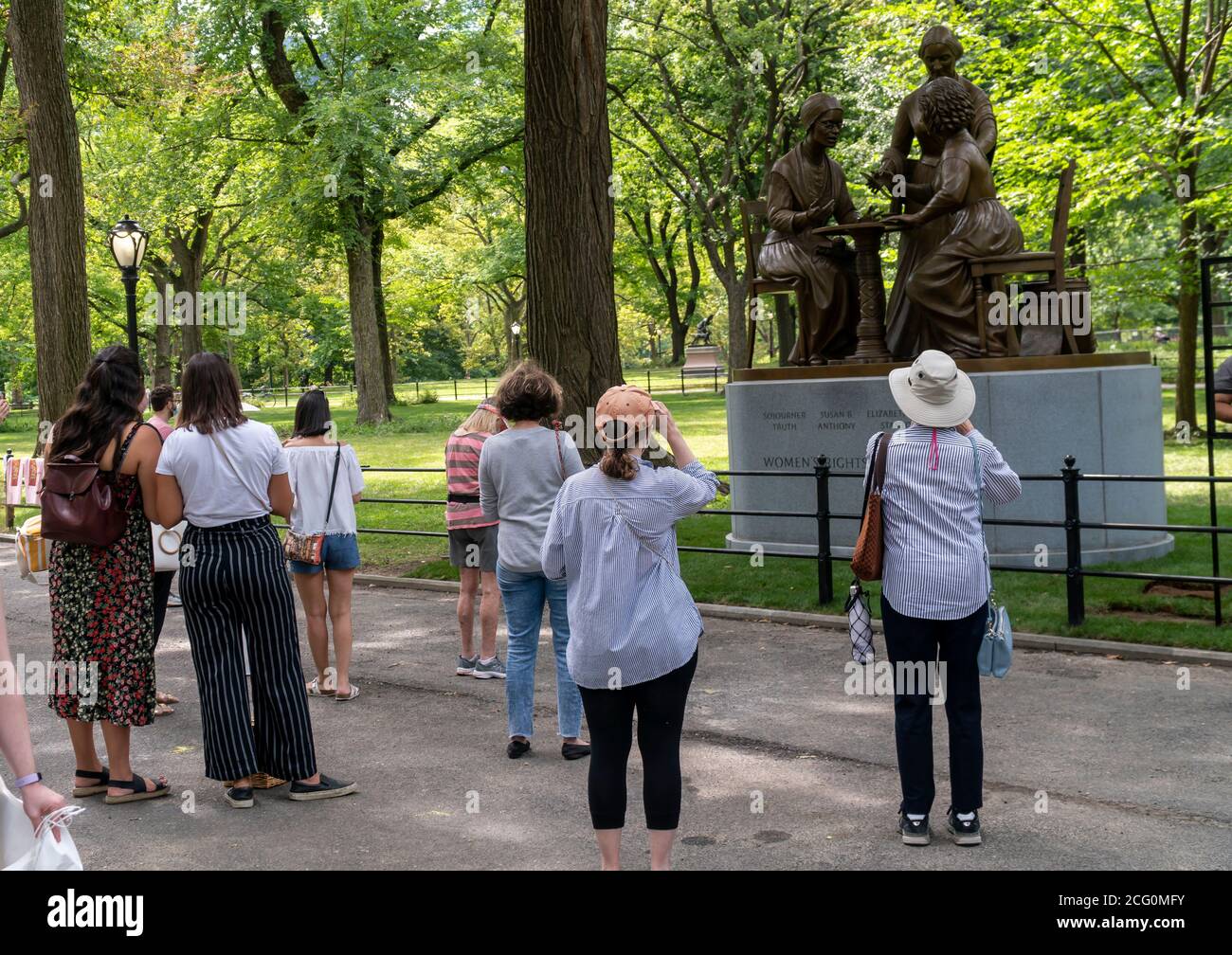 People cluster around the Women’s Rights Pioneer Monument on Literary