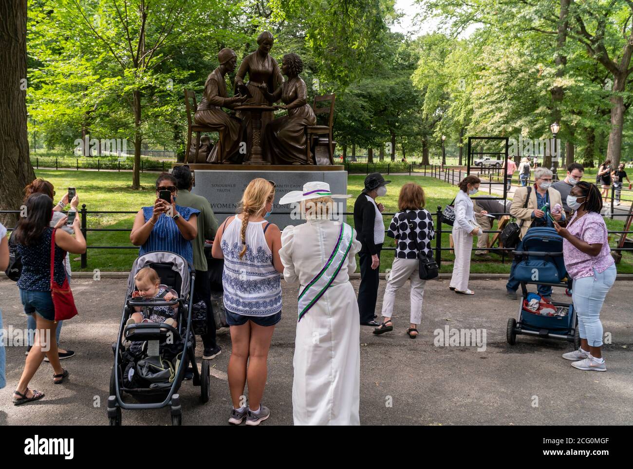 People cluster around the Women’s Rights Pioneer Monument on Literary