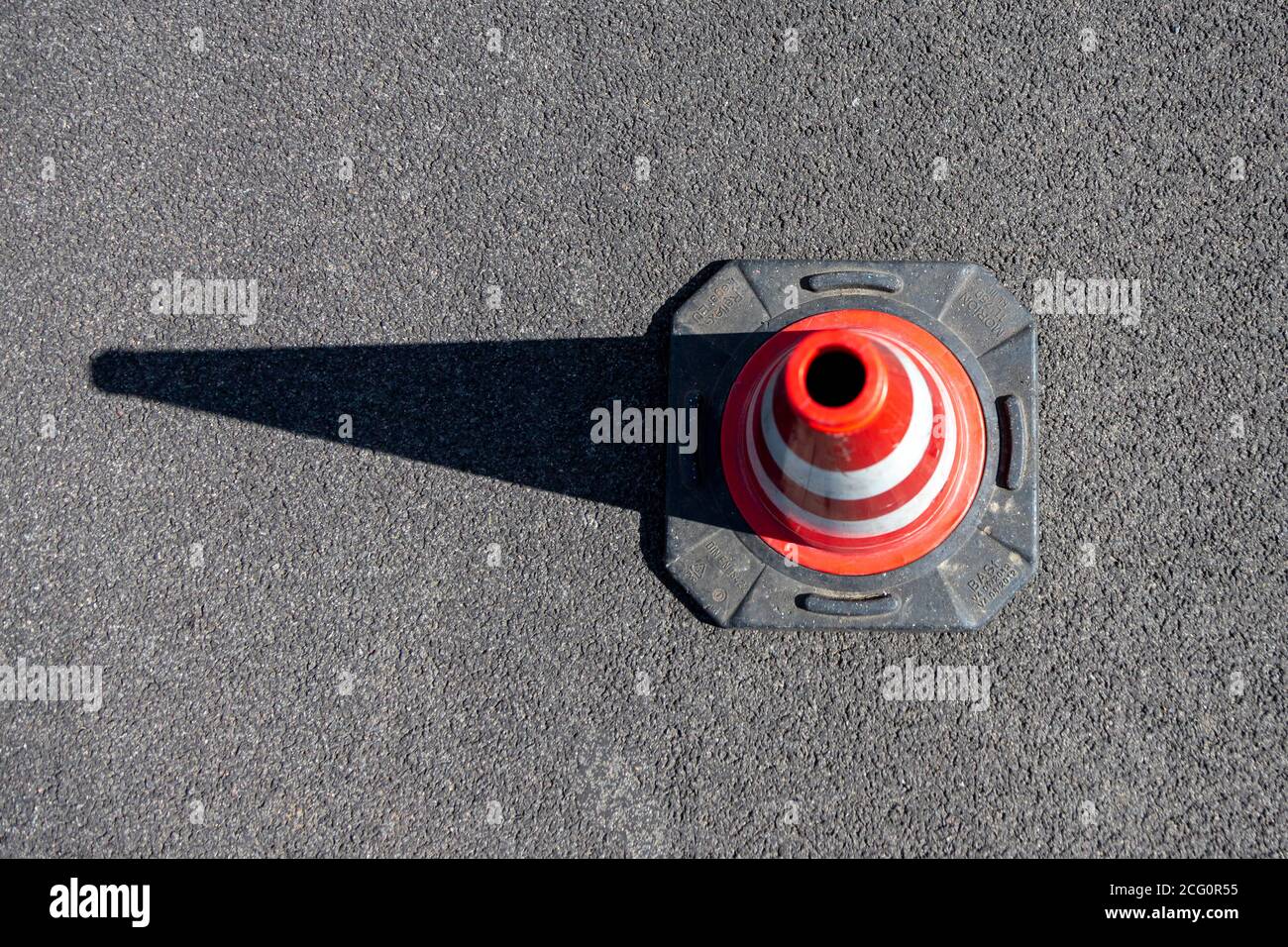 A single red striped traffic cone, pylon, on asphalt, outdoors Stock
