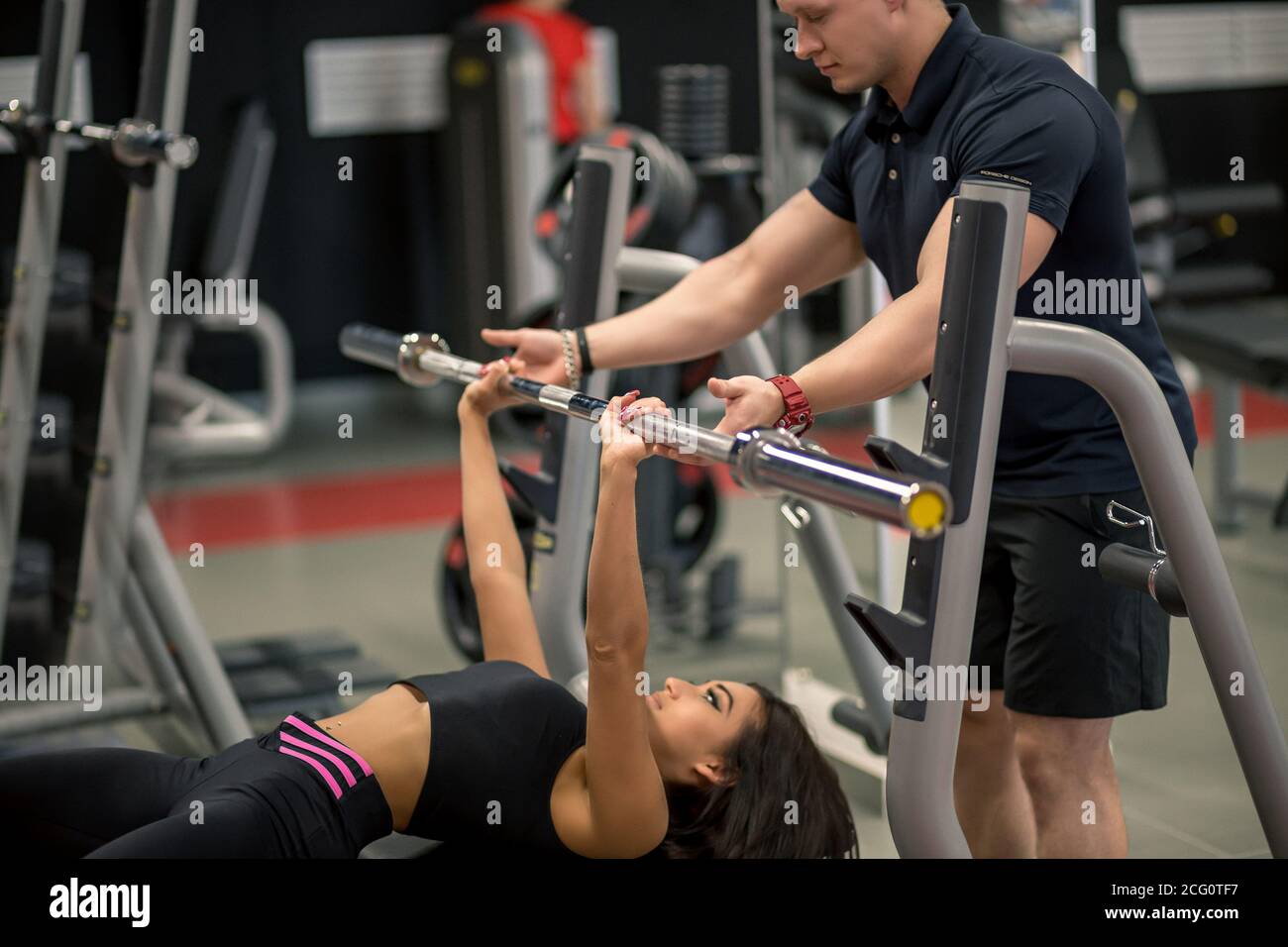 Personal trainer helping woman bench press in gym Stock Photo Alamy