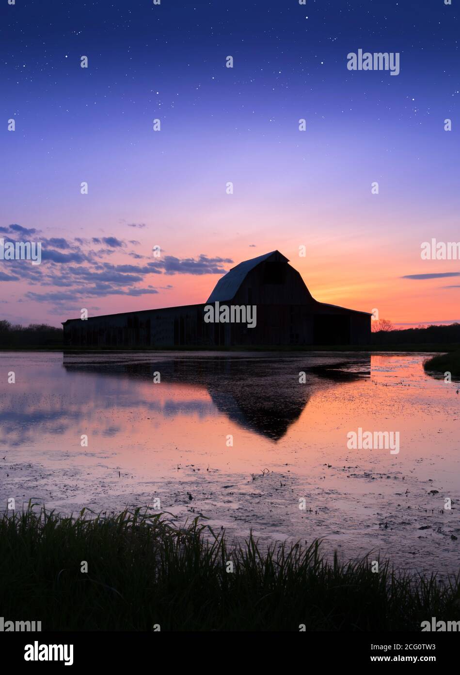 Old Barn and Sunset Reflected in Water Stock Photo