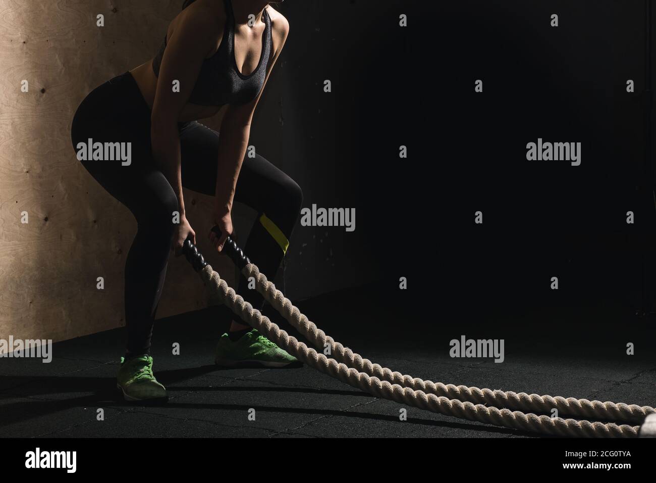 Athletic young woman doing some crossfit exercises with a rope outdoor ...