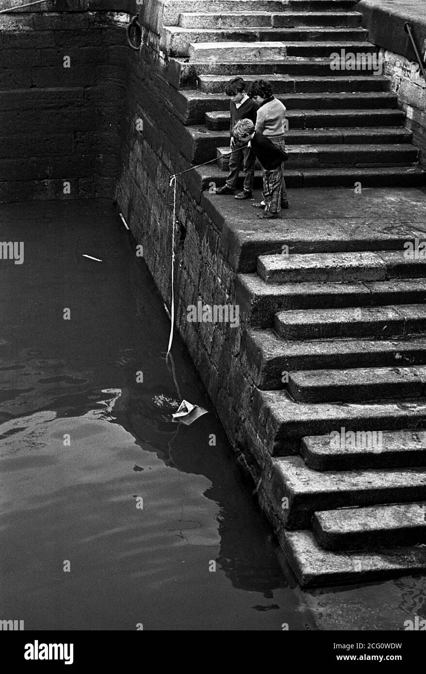 AJAXNETPHOTO. 1967. PORTSMOUTH, ENGLAND. - HOPING FOR A BITE - YOUNGSTERS WITH IMPROVISED FISHING TACKLE ON THE STEPS AT FLATHOUSE QUAY.PHOTO:JONATHAN EASTLAND/AJAX REF:356773 14 6 Stock Photo