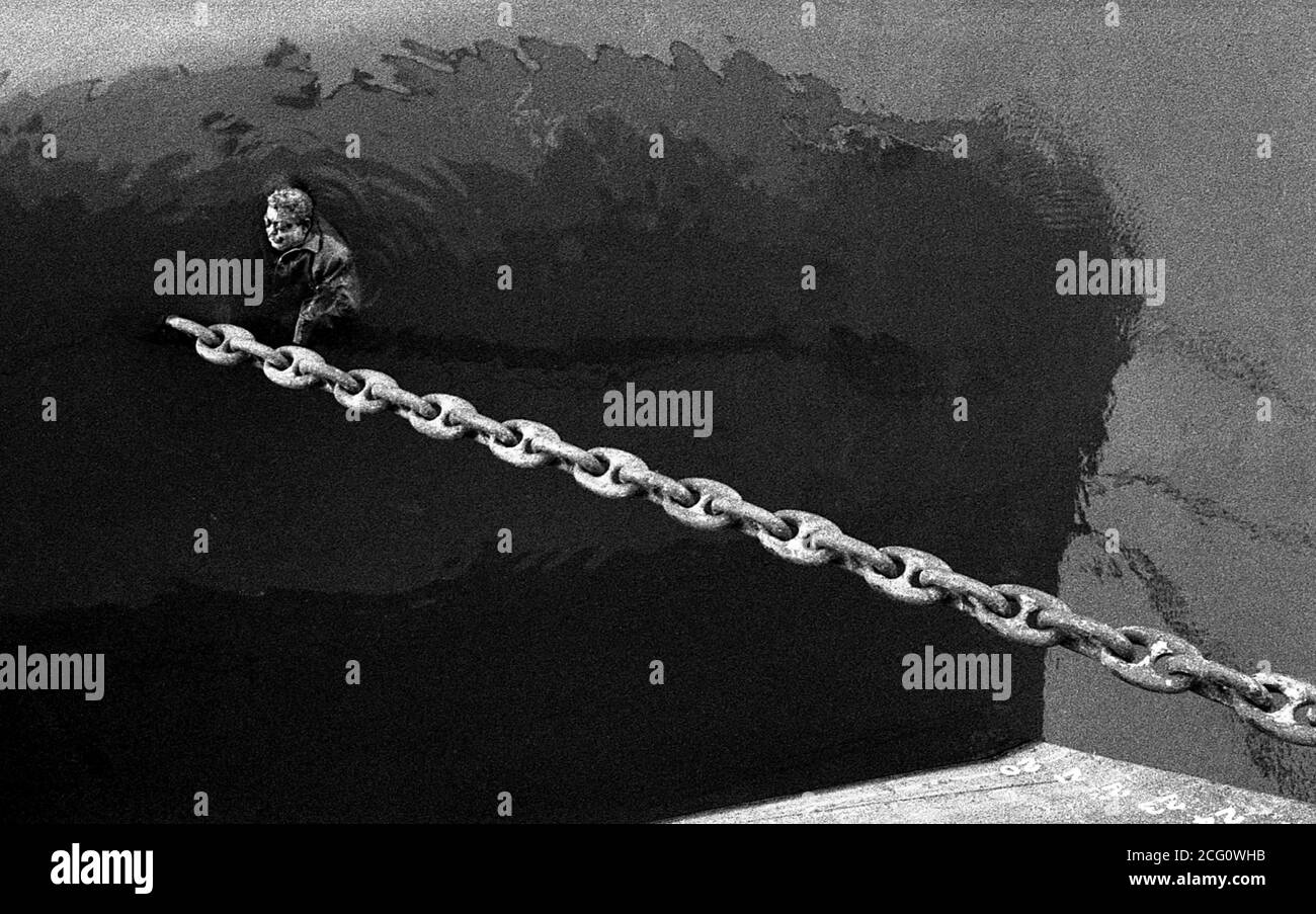 AJAXNETPHOTO. 1964. MONTEVIDEO, URUGUAY. - DOCK DEATH - THE BODY OF A MAN FLOATING IN THE DOCK AROUND THE ANCHOR CHAIN OF A CARGO SHIP.PHOTO:JONATHAN EASTLAND/AJAX REF:1964 115 Stock Photo