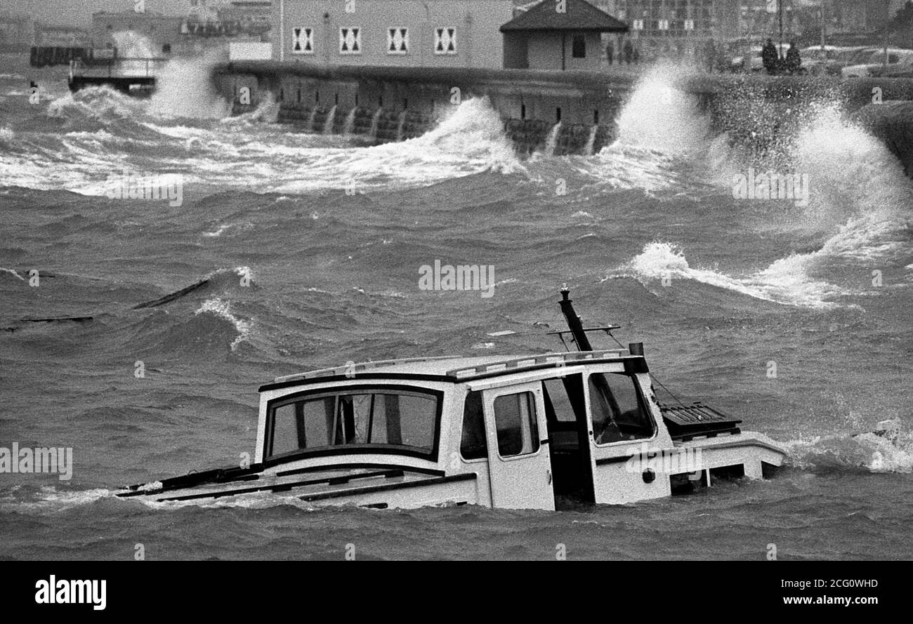 AJAXNETPHOTO. 1975. SOUTHSEA, ENGLAND. - WRECKED - A HALF SUNK MOTOR CRUISER THAT LOST ENGINE POWER DRIFTS ASHORE IN STORMY WEATHER SOON TO BE PUMMELED TO MATCH-WOOD BY THE WAVES.  PHOTO:JONATHAN EASTLAND/AJAX REF:75 10A 41 Stock Photo